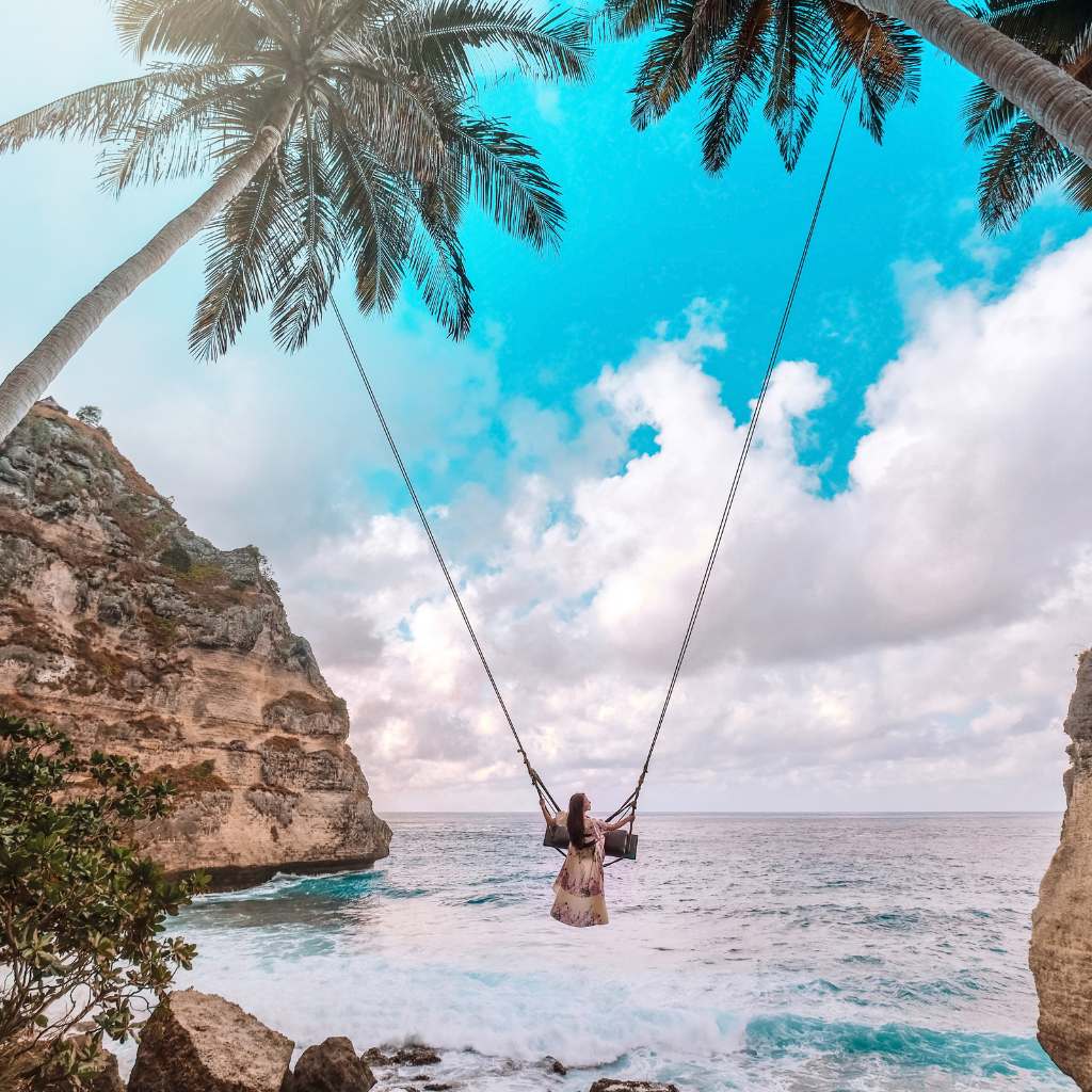 a woman playing on a swing at diamond beach